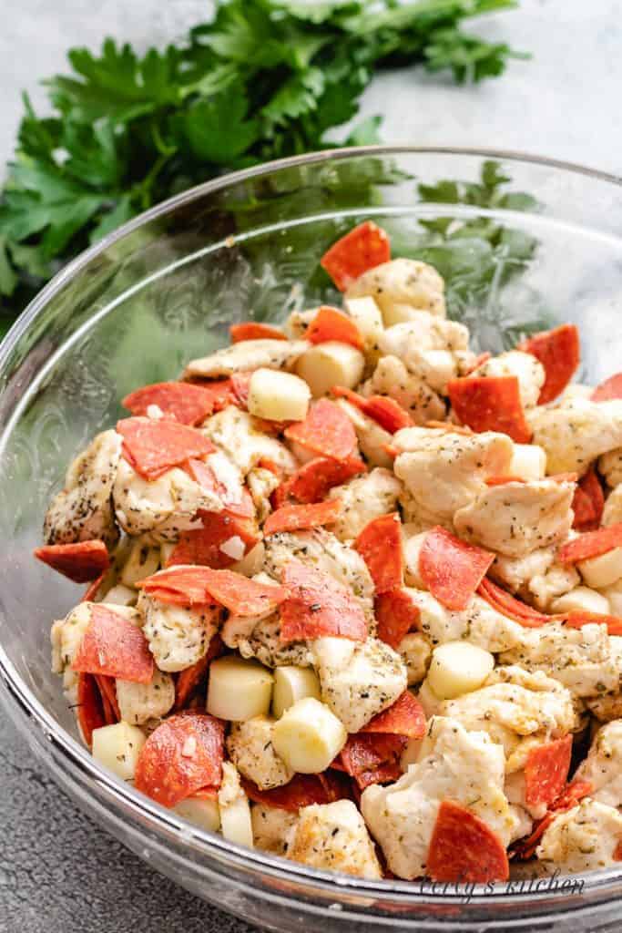 Pepperonis, biscuits, and other ingredients in a mixing bowl.