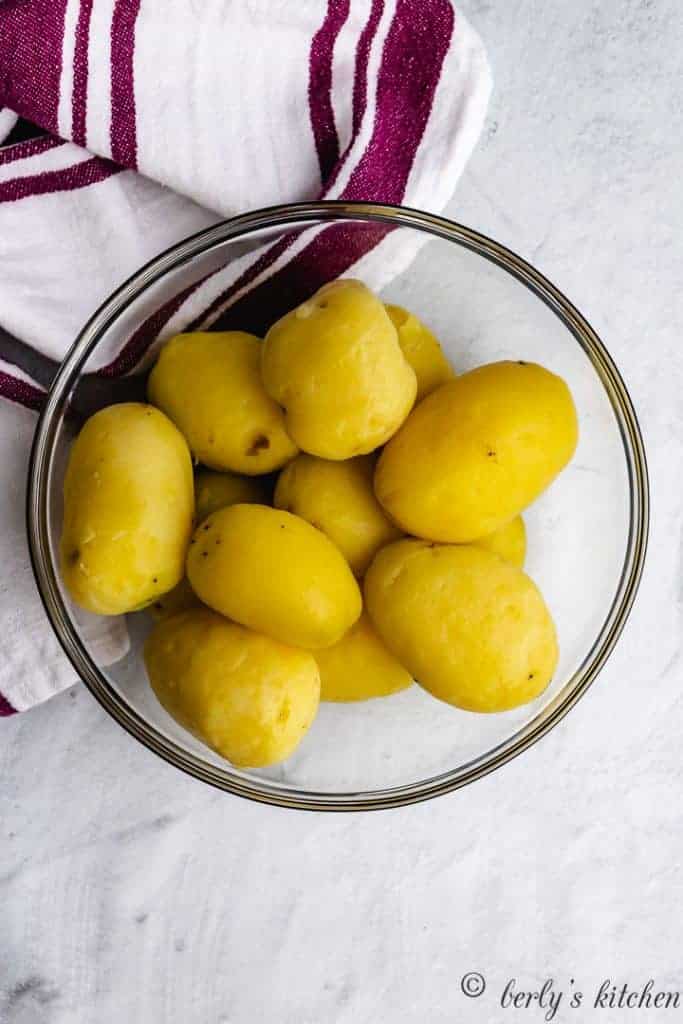 Boiled, peeled potatoes in a mixing bowl.