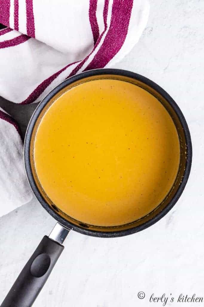 A cheddar cheese sauce warming in a saucepan.