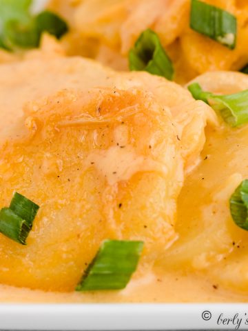 Creamy scalloped potatoes garnished with green onions.