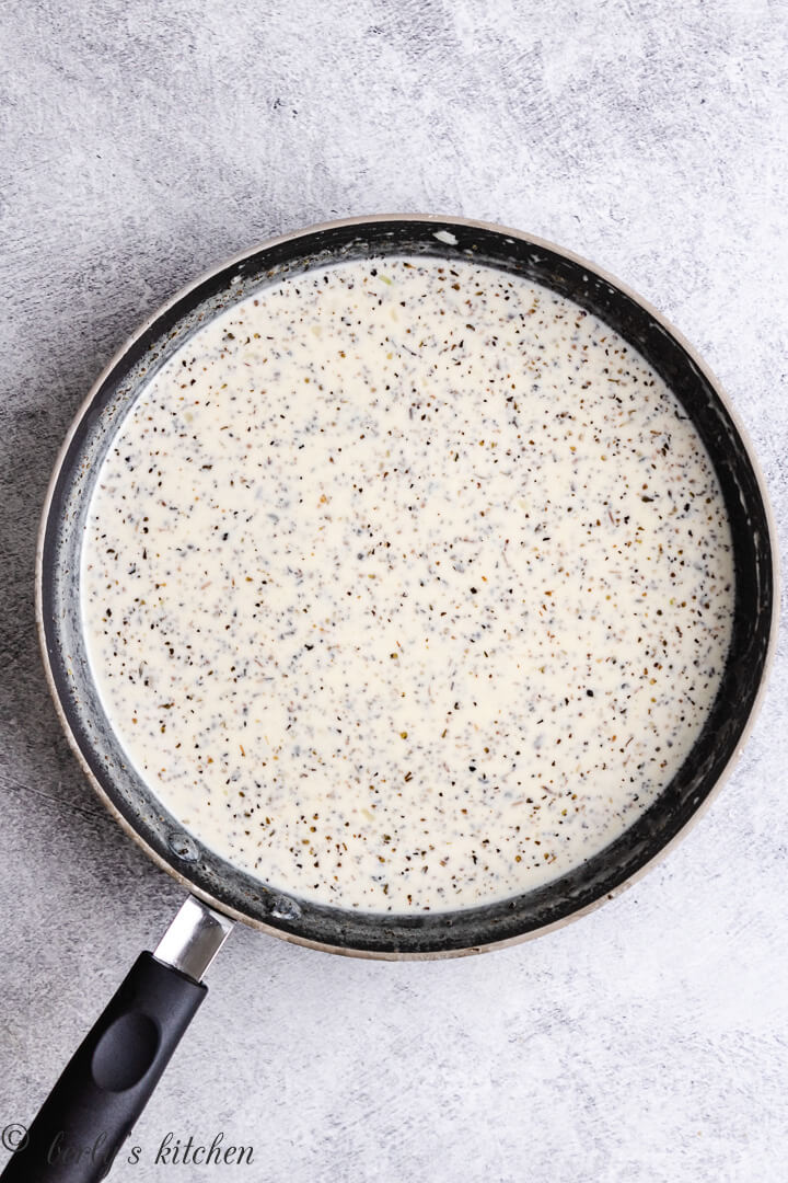 Heavy cream, spices, and other ingredients in skillet.