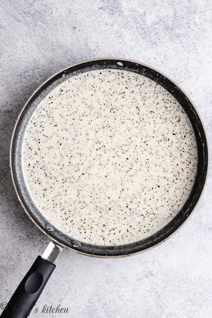 Heavy cream, spices, and other ingredients in skillet.