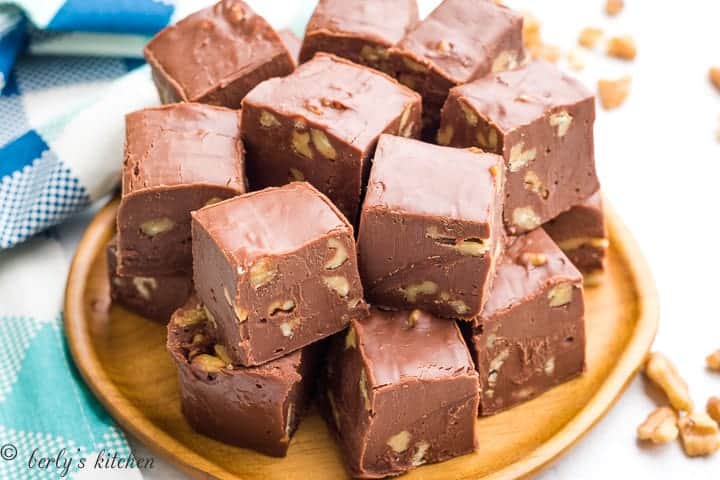 Chocolate walnut fudge squares served on a decorative wooden plate.