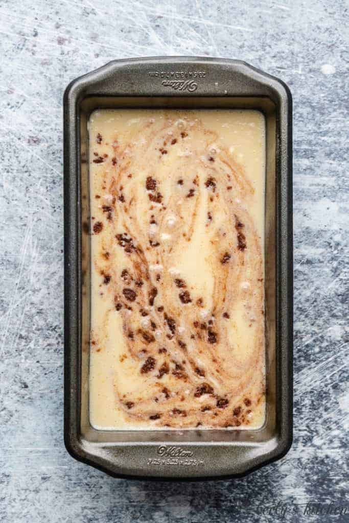 The batter and cinnamon mixture combined in a loaf pan.