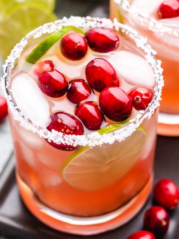 A cranberry margarita garnished with salt and fresh cranberries.