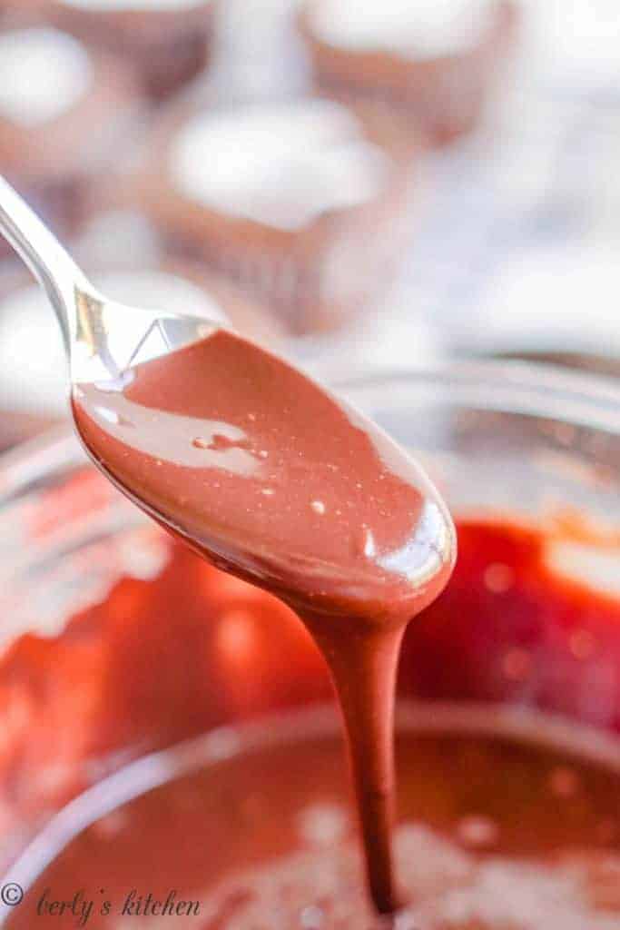 A spoon being lifted out of the smooth frosting.