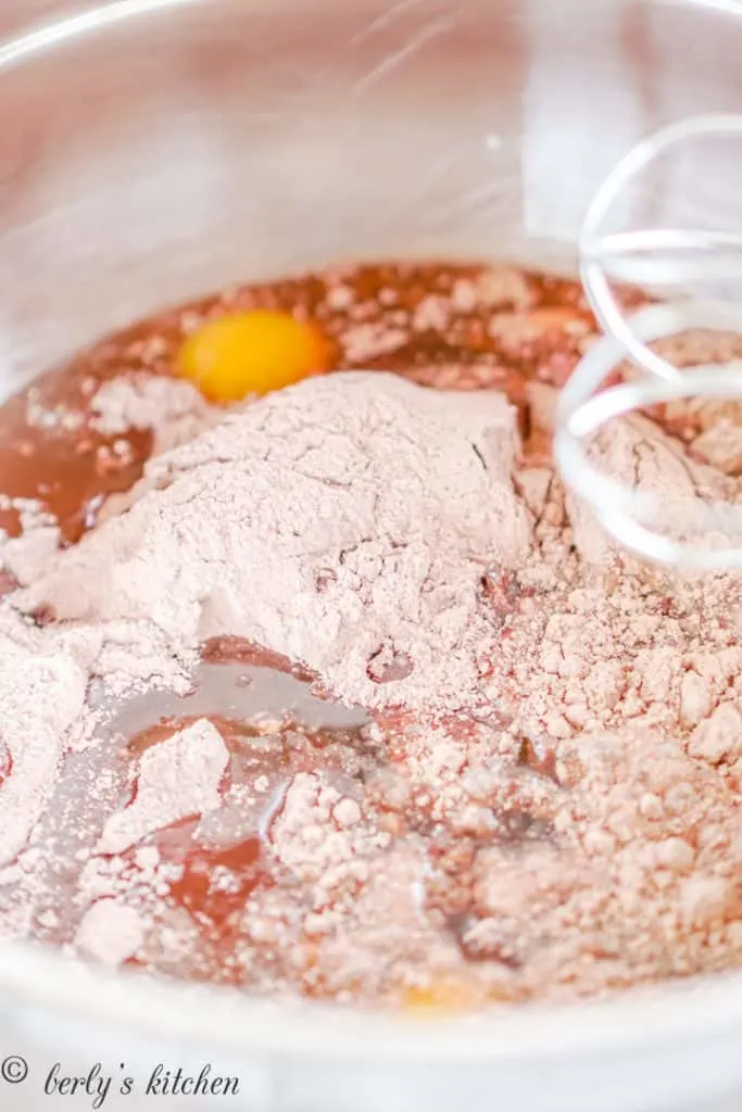 Cake mix, cracked eggs, and other ingredients in a mixing bowl.