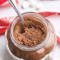 Hot chocolate mix in a jar with a spoon.
