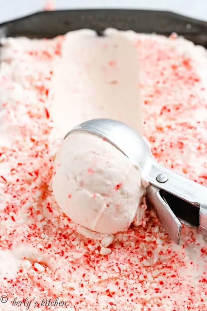 An ice cream scoop removing some of the frozen dessert.