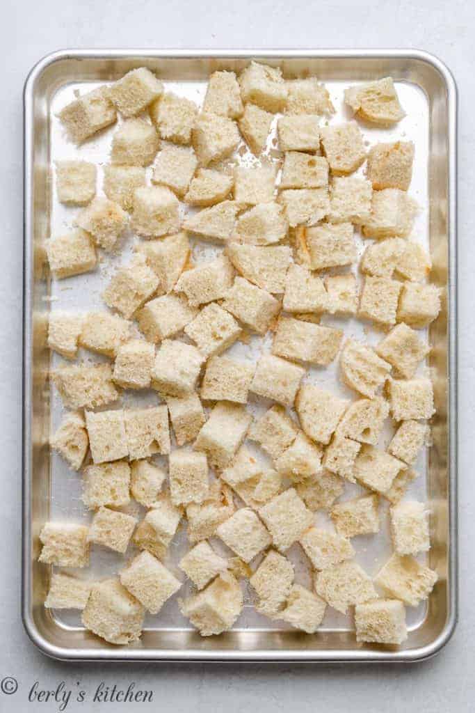 Cubes of french bread on a sheet pan.