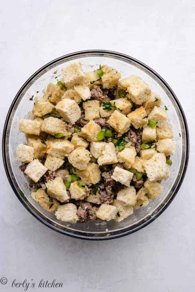 The meat and veggies combined with toasted bread in a mixing bowl.