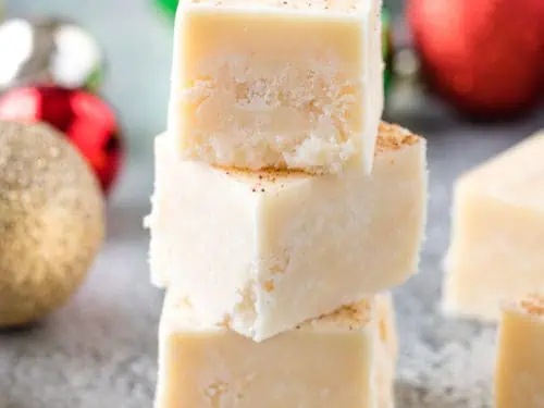 Three pieces of eggnog fudge stacked on each other.