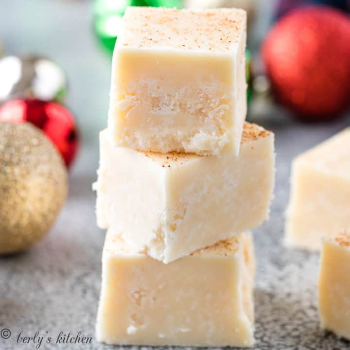 Three pieces of eggnog fudge stacked on each other.