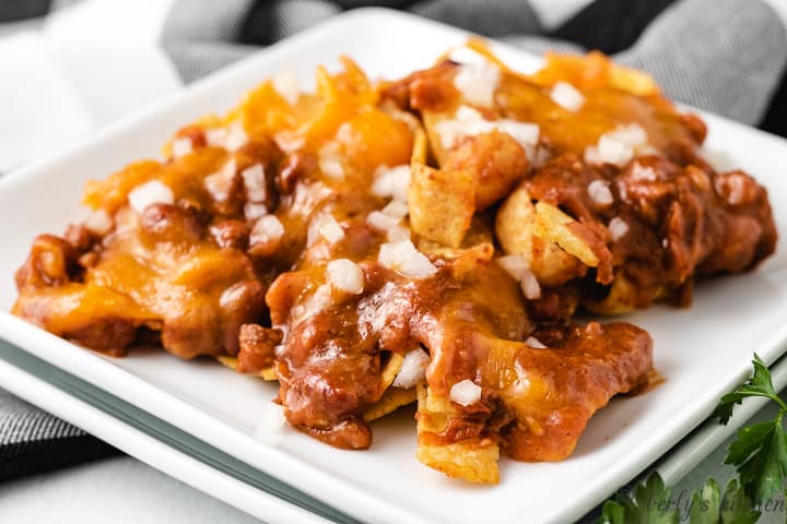 The cheesy frito pie served on a square plate.