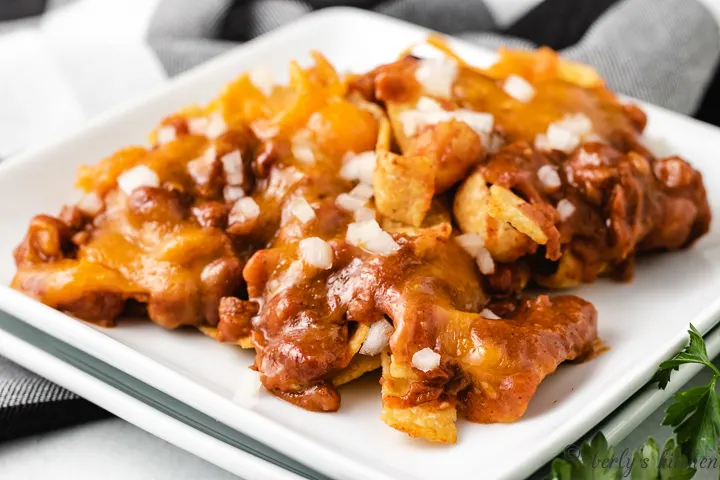 The cheesy frito pie served on a square plate.