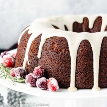 Gingerbread bundt cake with icing next to sugared cranberries.