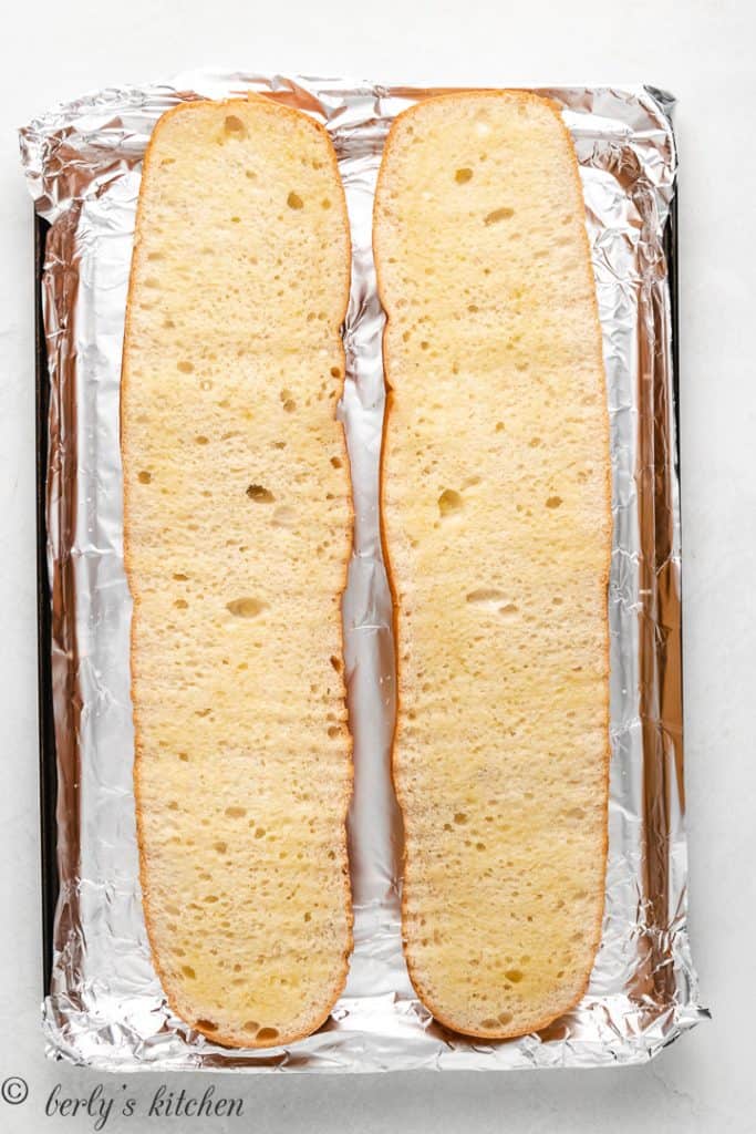 Sliced french bread on a baking sheet lined with aluminum foil.