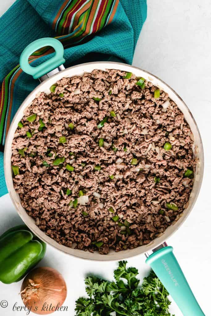 Top down view of ground beef, onion, and peppers in a skillet.