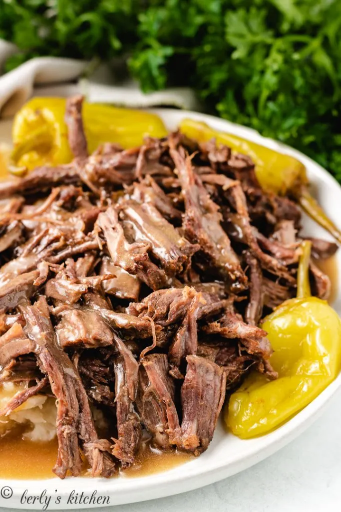 Pulled mississippi roast and pepperoncini peppers on a plate.