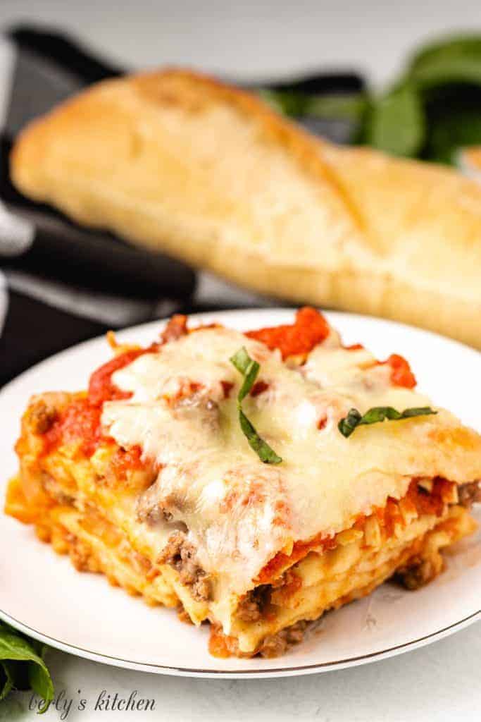 A slice of lasagna served with bread.