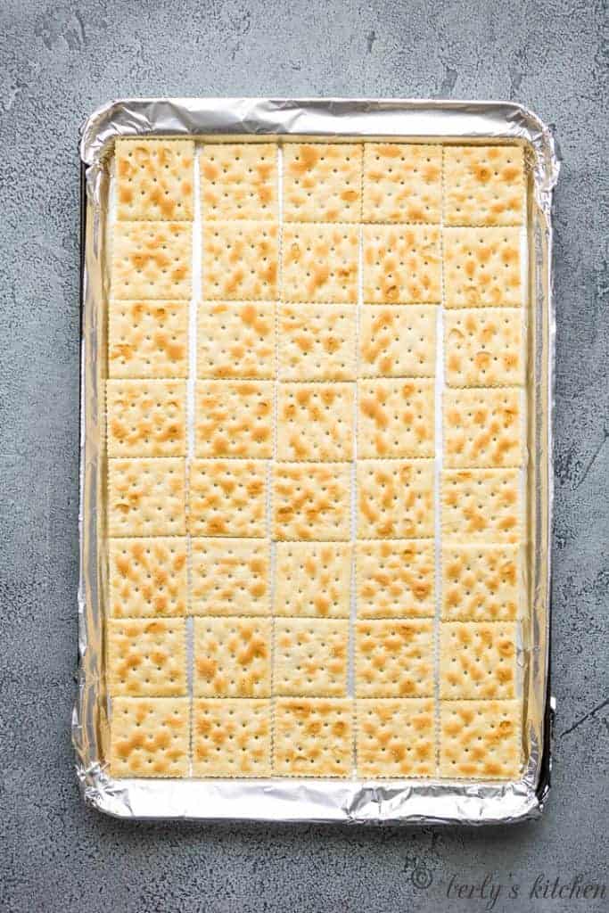 Soda crackers placed in a lined sheet pan.