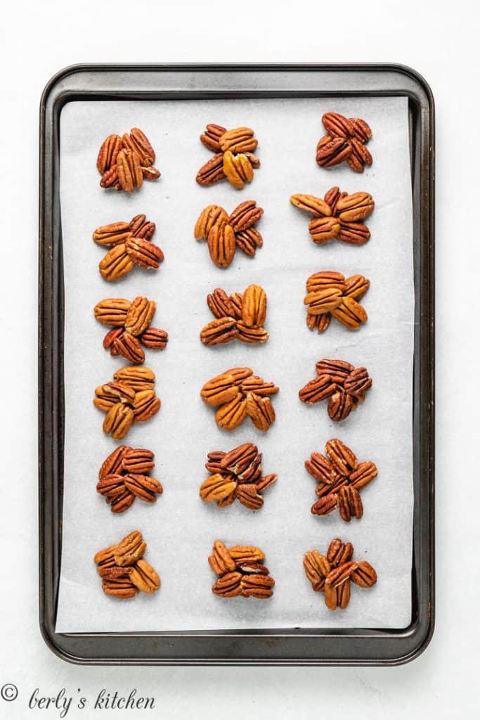 Pecan clusters on a lined baking sheet.