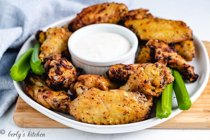 Air fryer lemon pepper wings on a plate with ranch dressing.