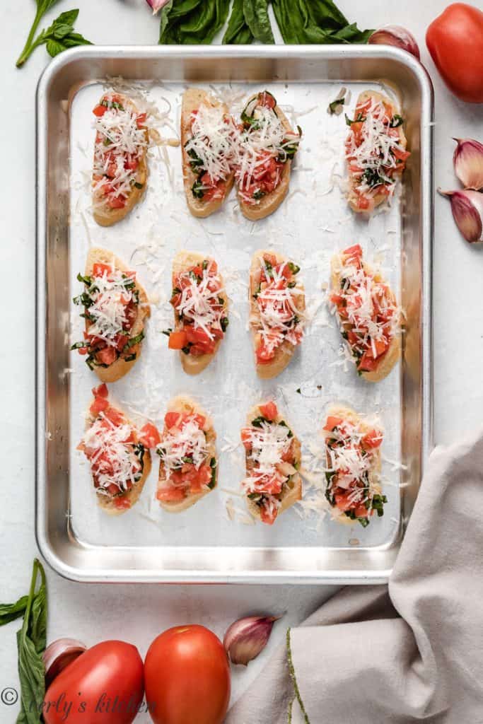 Top down photo of sliced bread with bruschetta and cheese.
