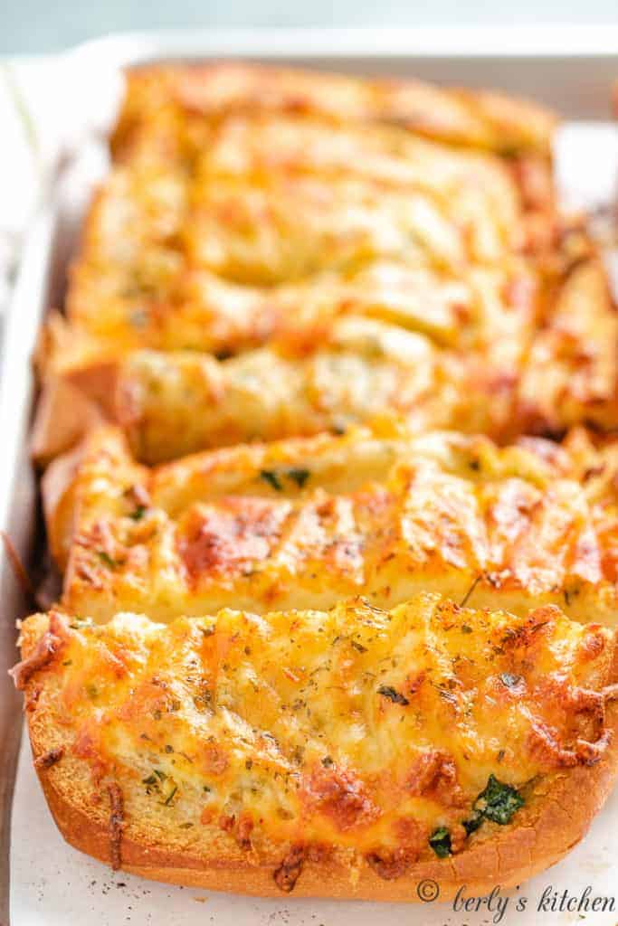 Sliced cheesy garlic bread on a sheet pan.