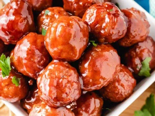 Close up of meatballs in a square bowl.