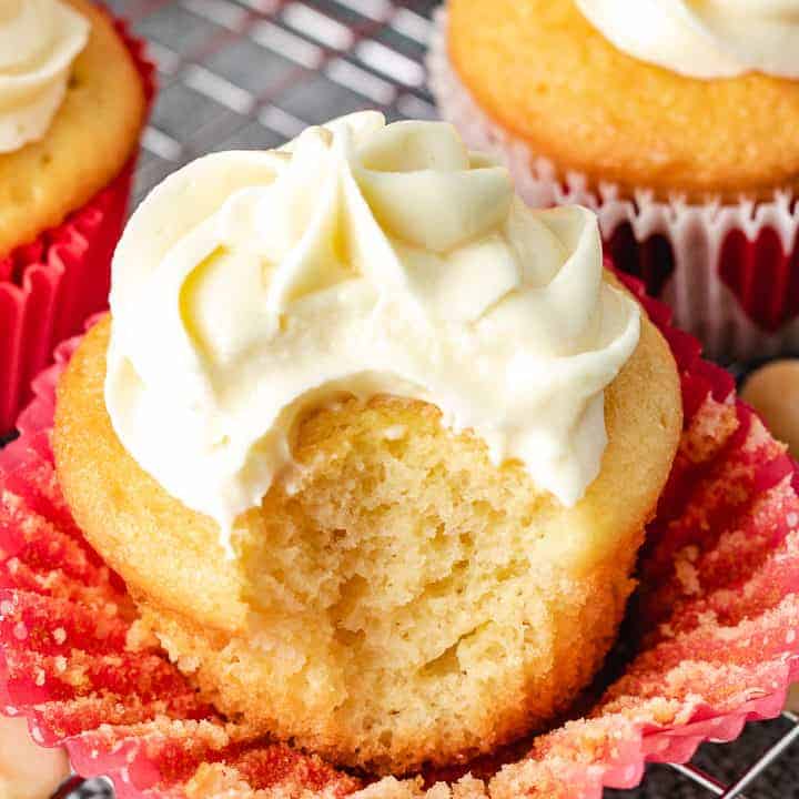 Bite taken out of a macadamia cupcake with white chocolate frosting.