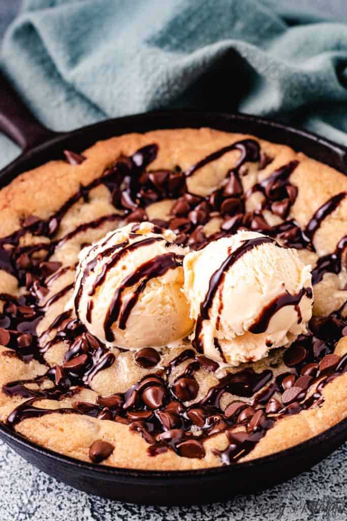 Skillet cookie topped with vanilla ice cream and chocolate syrup.