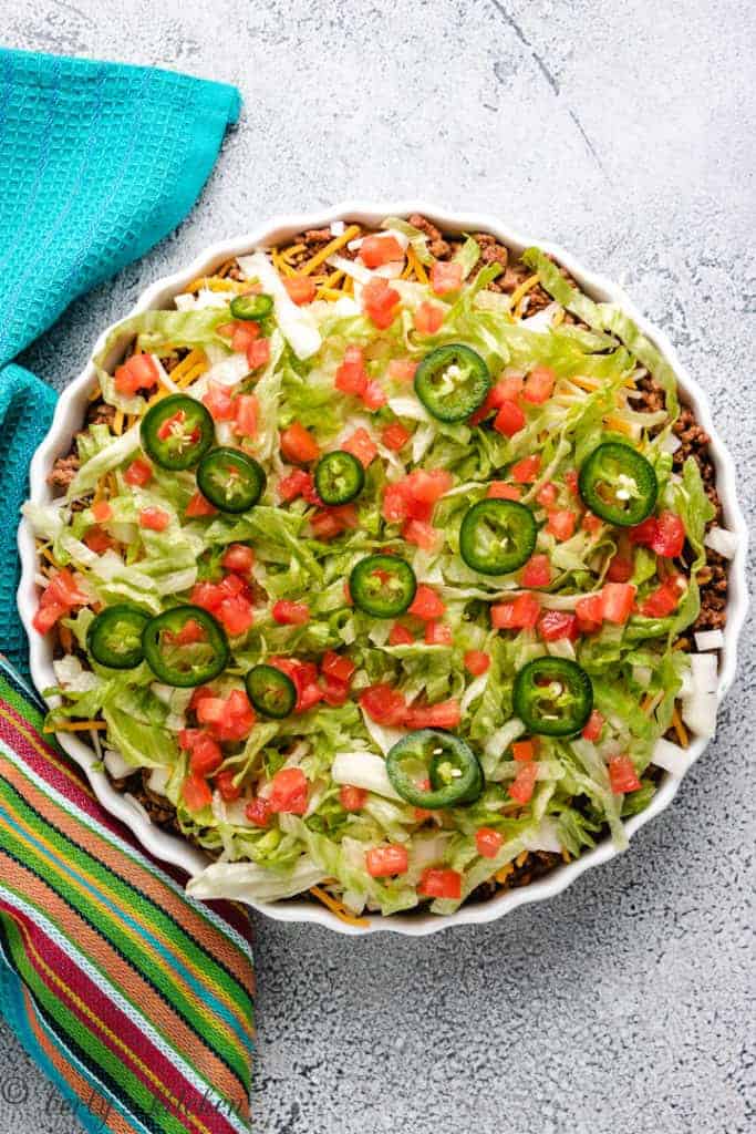 Taco dip in a bowl with a blue towel.