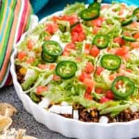 Taco dip with fresh tomatoes, cheese, and lettuce.