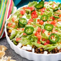 Taco dip with fresh tomatoes, cheese, and lettuce.
