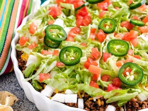 Taco dip with fresh tomatoes, cheese, and lettuce.