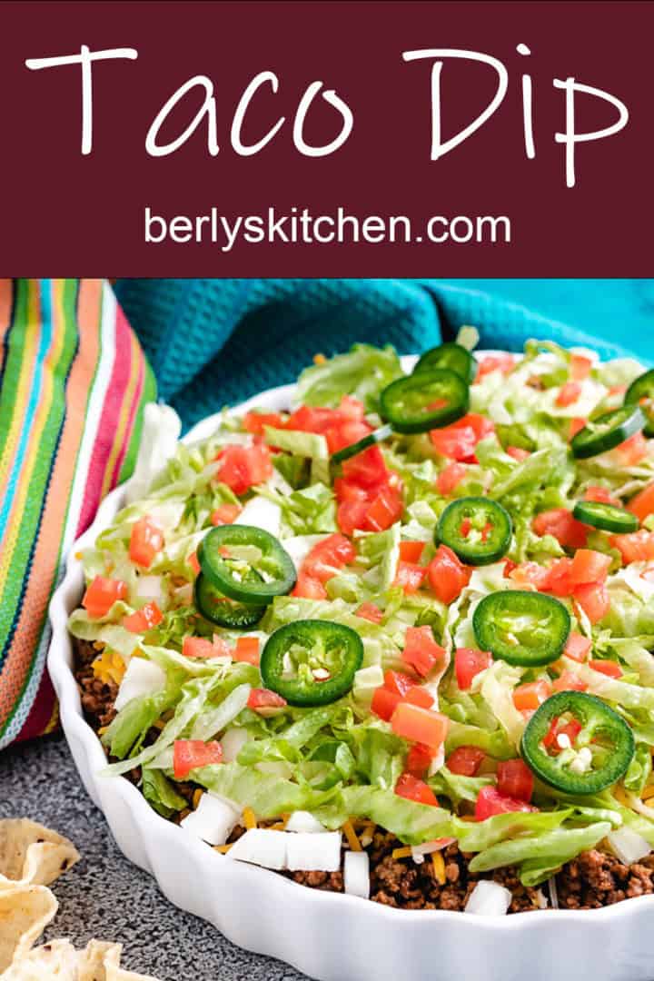 Serving bowl of taco dip with lettuce and tomatoes.