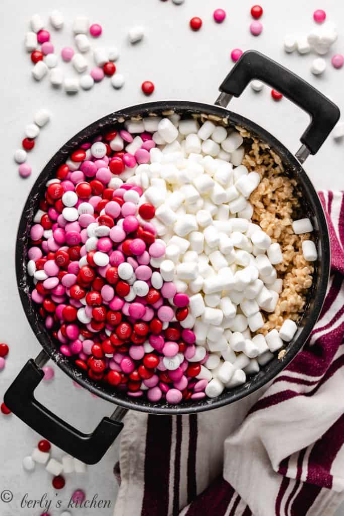 Unmixed rice krispie treats with extra marshmallows and chocolate candy in a pan.