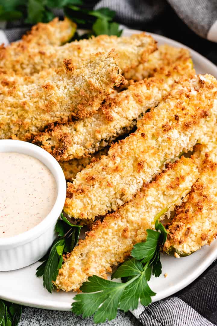 Several fried pickle spears on a plate with dressing.