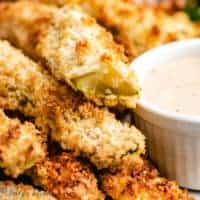 Air fried pickles on a plate with dressing.