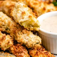 Air fried pickles on a plate with dressing.