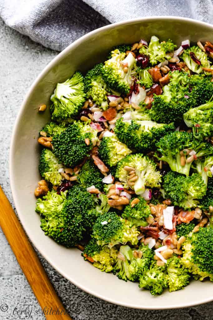 Broccoli in a bowl with seeds, nuts, and dressing.
