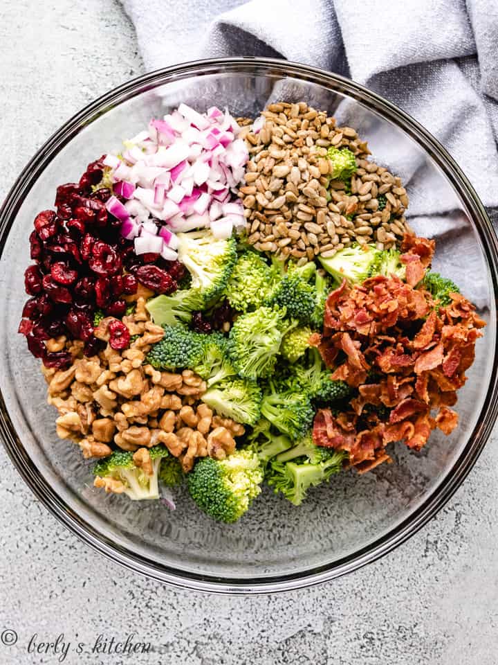 Cranberries, nuts, seeds, broccoli, and onions in a bowl.