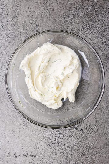 Cream cheese, dill, and pickle juice mixed in a bowl.