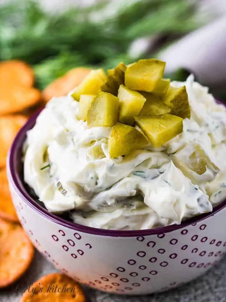 Dill pickle dip in a purple and white bowl.
