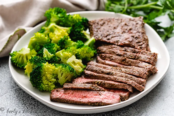 Seasoned steak with fresh steamed vegetables on a white plate.
