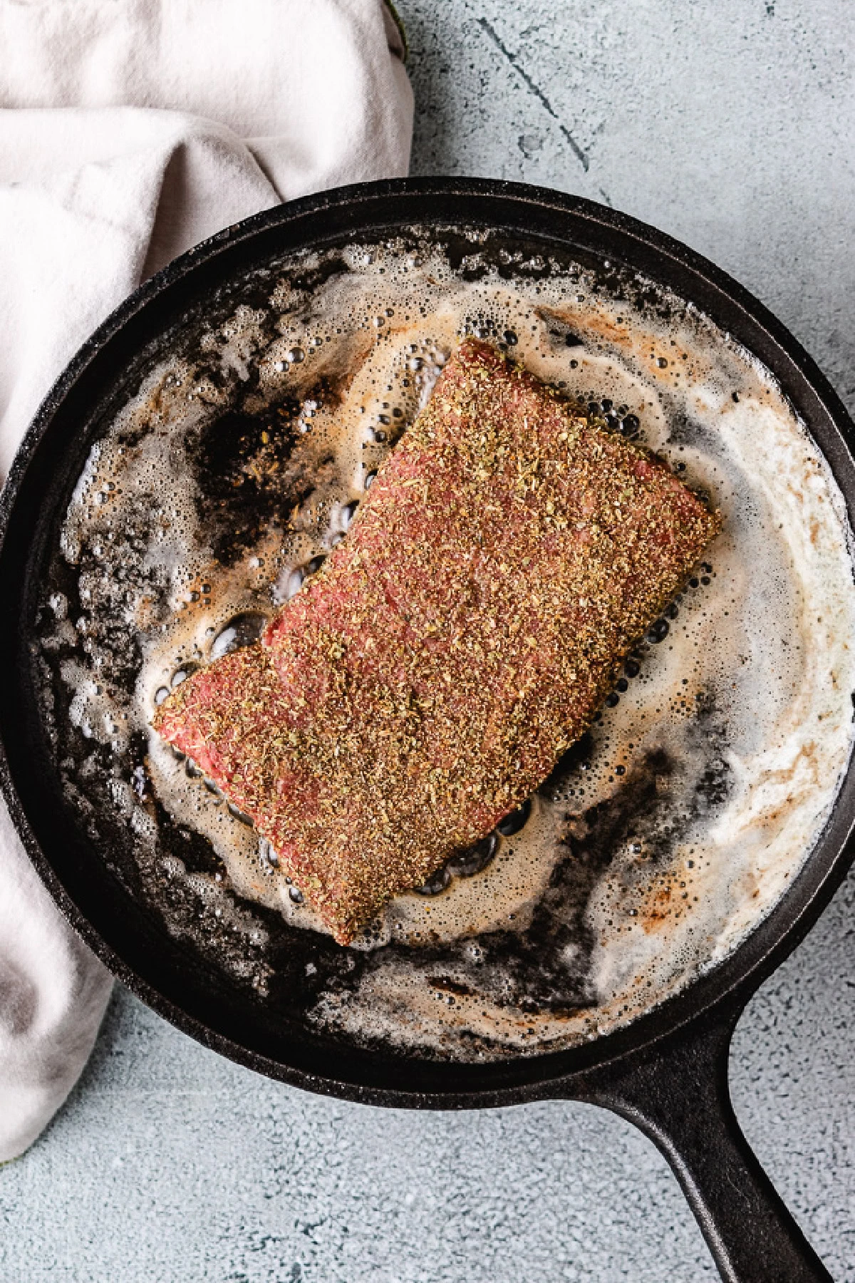 Flat iron steak cooking in butter.