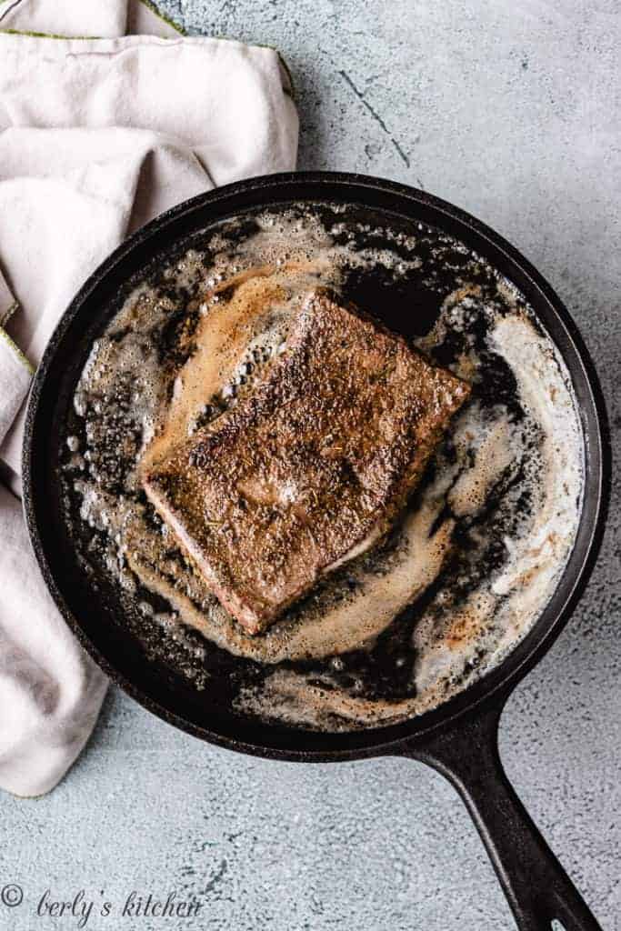 Cooked flat iron steak cooked on a cast iron skillet.