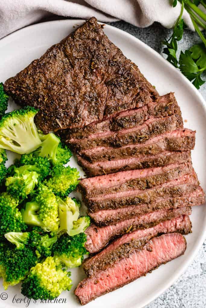 Cooked steak and steamed broccoli on a gray dish.