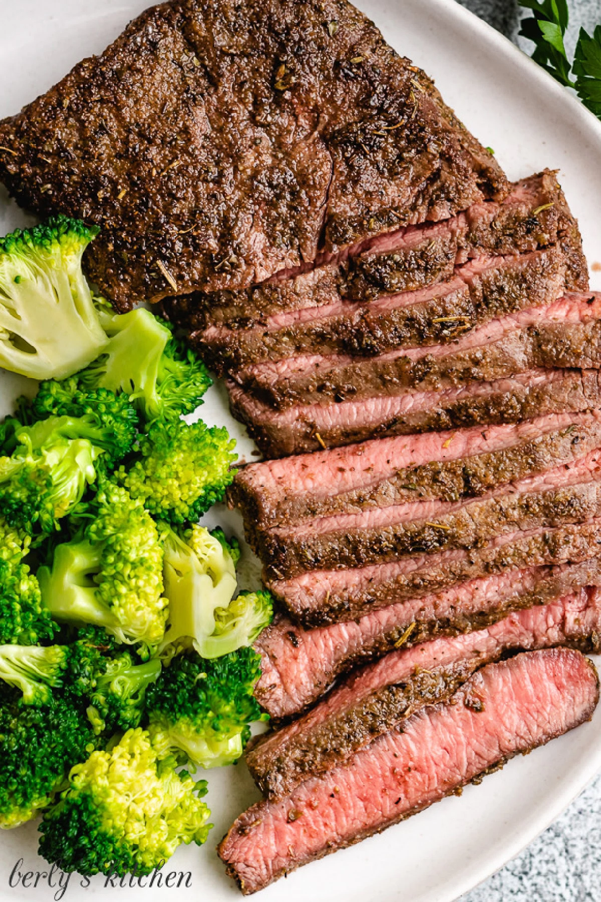 Cooked steak and steamed broccoli on a gray dish.